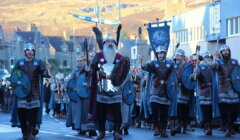 A group of men dressed in armor walking down a street.