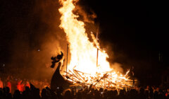 A large group of people watching a bonfire.