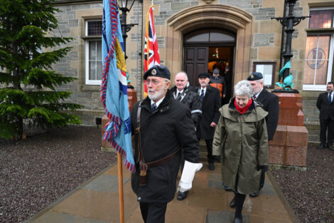 A group of people carrying a flag in front of a building.