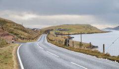 A paved road next to a body of water.