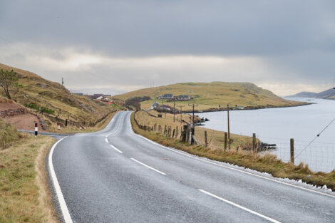 A paved road next to a body of water.