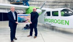 Two men standing in front of a green plane.