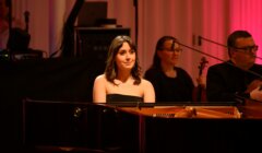 A woman playing a piano in front of a group of people.