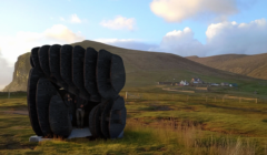 A black sculpture in the middle of a grassy field.