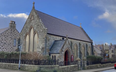 A red car is parked in front of a church.