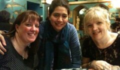 Three women posing for a photo at a restaurant.