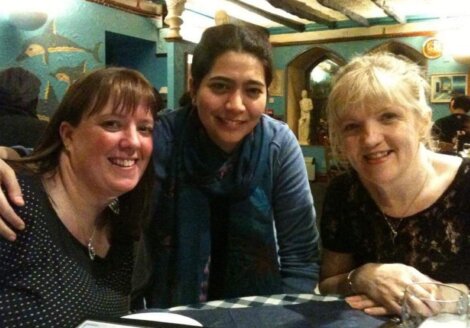 Three women posing for a photo at a restaurant.