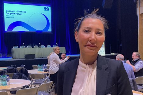 A woman in a suit standing in front of a conference room.