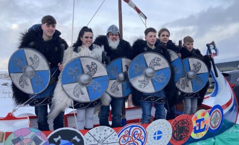 A group of people posing for a photo on a viking boat.