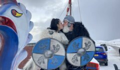 A couple kisses in front of a viking sleigh.