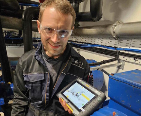 A man holding a tablet in front of a machine.