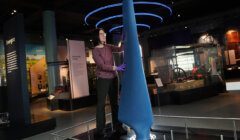 A woman standing next to a blue object in a museum.