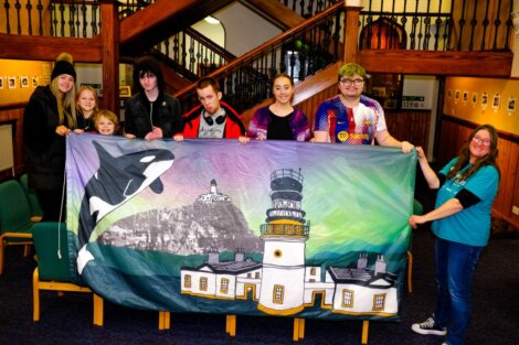 A group of people holding a large banner.