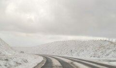 A car driving down a snow covered road.