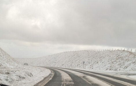 A car driving down a snow covered road.