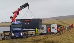 A truck with a crane lifting a large container.