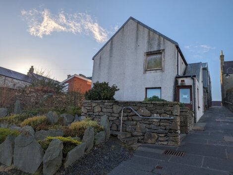 A stone house with a stone wall in front of it.