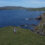 A person is standing on a grassy hill overlooking the ocean.