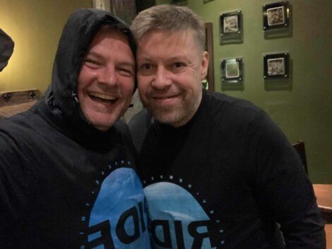 Two men posing for a photo wearing ride t - shirts.