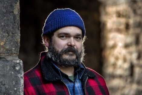 A bearded man wearing a beanie and plaid shirt.