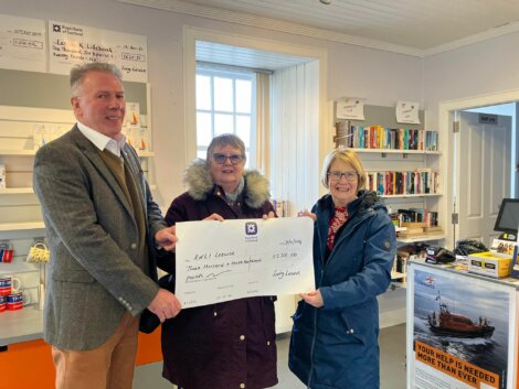 Three people standing in front of a store with a check.