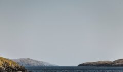 A large body of water with a hill in the background.