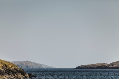 A large body of water with a hill in the background.