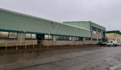 An industrial building with cars parked in front of it.