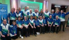 Group of people in matching team shirts posing for a photo indoors.