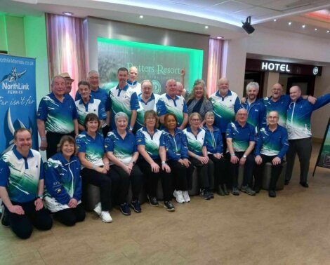 Group of people in matching team shirts posing for a photo indoors.