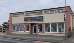 A two-story home furnishings store with large display windows on the ground floor.