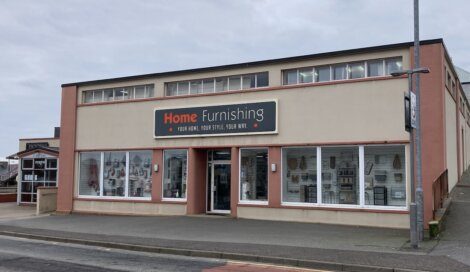 A two-story home furnishings store with large display windows on the ground floor.