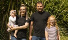 A family of four with two adults and two children posing for a photo outdoors.