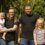 A family of four with two adults and two children posing for a photo outdoors.