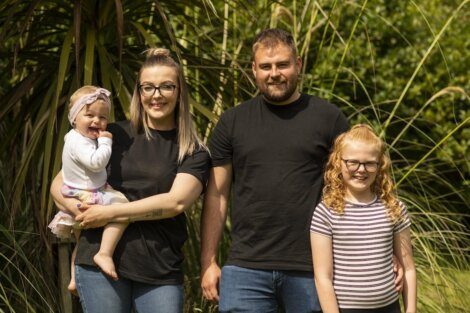 A family of four with two adults and two children posing for a photo outdoors.