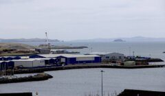 Industrial waterfront with warehouses and a view of the distant islands.