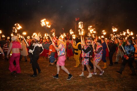 People participate in a torchlight procession at night during a festival.