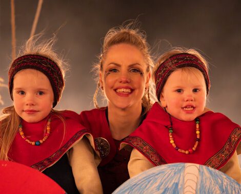 Three people in traditional attire with joyful expressions.