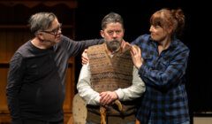 Two actors comforting a distressed colleague on stage.