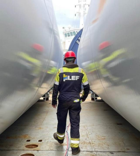 Worker inspecting the space between two large industrial tanks.