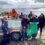 Group of volunteers participating in a coastal cleanup activity on a sunny day.