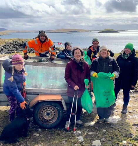 Group of volunteers participating in a coastal cleanup activity on a sunny day.