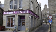 Tourist information center located on a corner of a quaint street with directional signs.