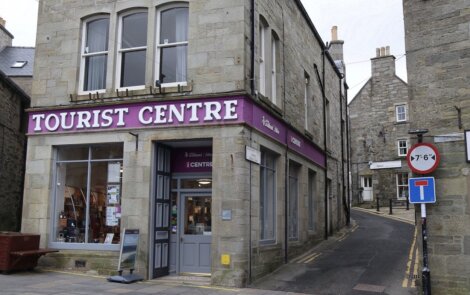 Tourist information center located on a corner of a quaint street with directional signs.