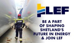 Worker with LEF logo standing between large industrial cylinders.