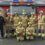 Group of firefighters standing in front of a fire truck at the station.