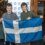 Two individuals holding the flag of scotland indoors.