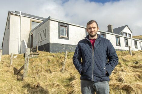 A man standing in front of a building with the word "inn" on the facade.