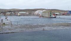 Harbor with boats and buildings on an overcast day with visible water level rising over the dock.