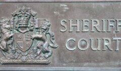 Bronze plaque with the text "sheriff court" beneath a relief of a coat of arms flanked by two heraldic beasts.